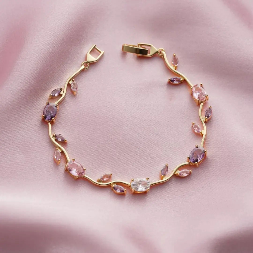 AVIOX gold-toned floral bracelet with multi-colored oval gemstones on pink satin fabric