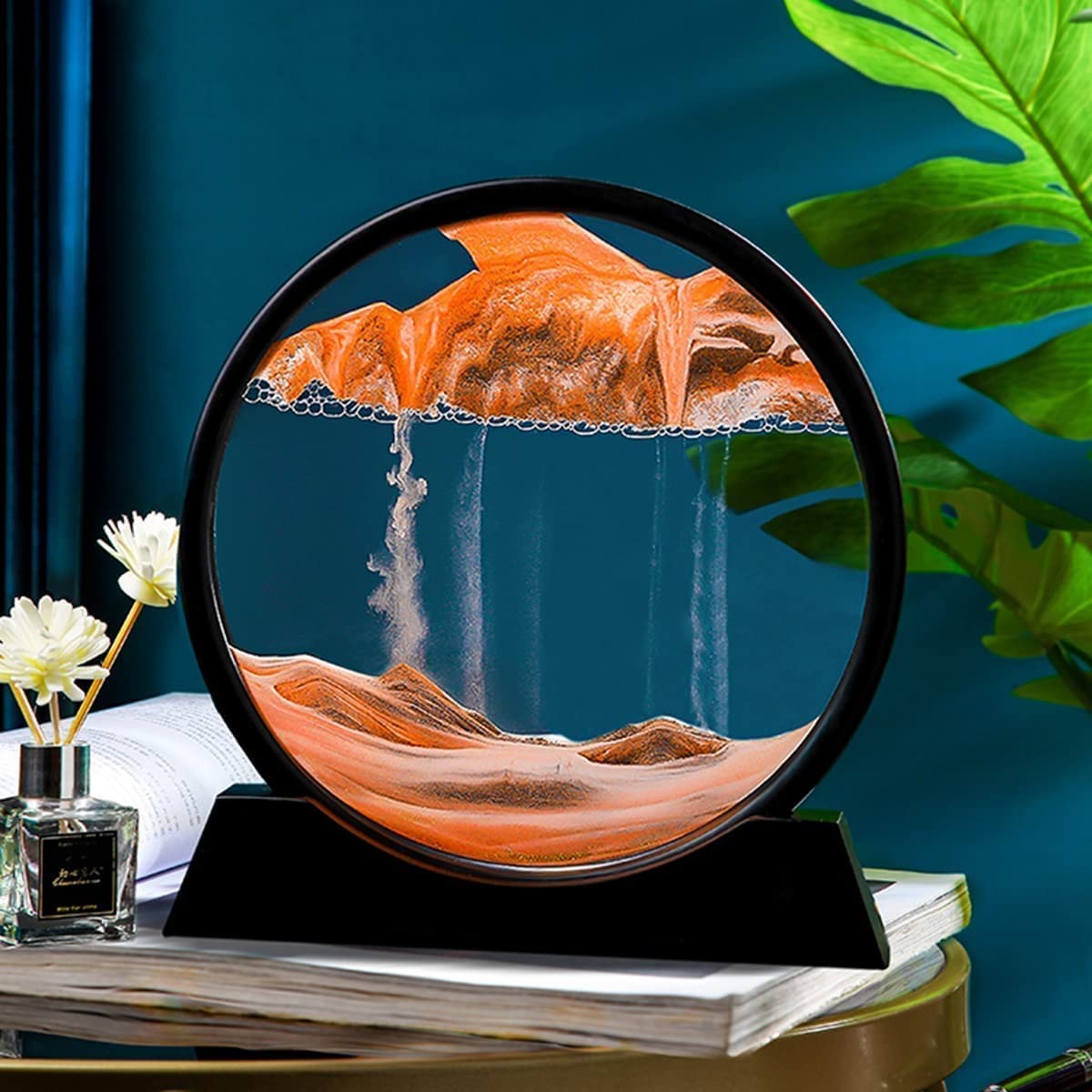 AVIOX 3D moving sandscape painting with orange sand dunes in a circular glass frame.