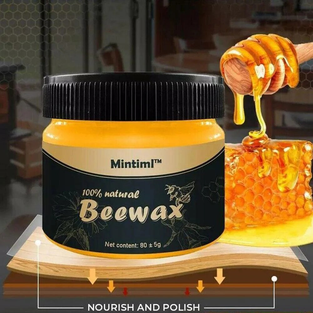 AVIOX Beeswax Furniture Polish jar next to honeycombs and a honey dipper on a wood surface.