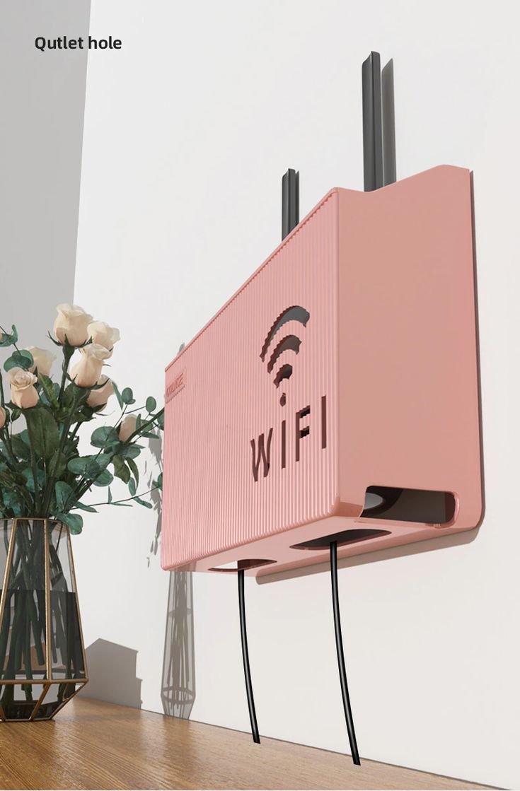 Pink AVIOX router storage box with WiFi logo mounted on a white wall to hide wires.