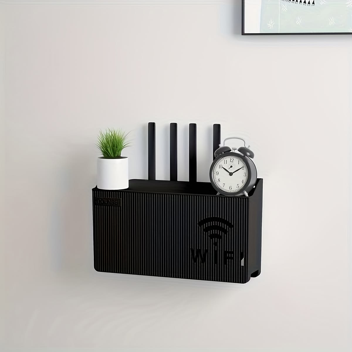 Black AVIOX router storage box mounted on a wall with a small plant and alarm clock.
